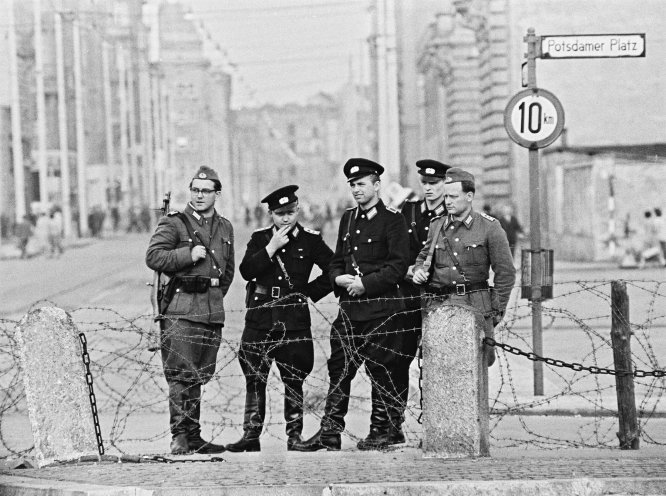 Soldaten der Volkspolizei (dunkle Uniform) und der Nationalen Volksarmee überwachen am 13. August 1961 den Bau der Mauer am Potsdamer Platz. Quelle: REGIERUNGonline