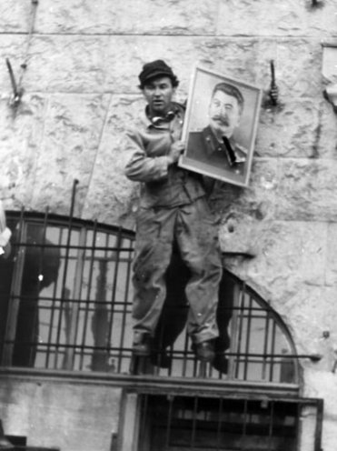 Ein Ostberliner Arbeiter entfernt ein Stalin-Portrait.