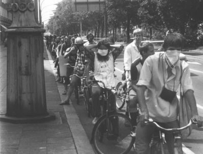 Fahrraddemo gegen verpestete Luft (4. Juli 1982): Die Radler wollen auf die zunehmende Umweltzerstörung in den Städten der DDR aufmerksam machen und binden sich auf der Straße Unter den Linden Tücher vor Mund und Nase.
