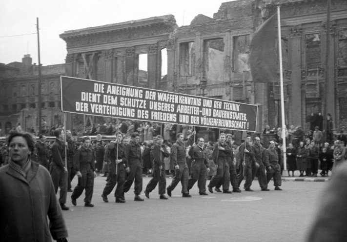 14. Mai 1956 in Ost-Berlin: Mitglieder der Gesellschaft für Sport und Technik (GST) demonstrieren. Auf dem Transparent steht: „Die Aneignung der Waffenkenntnis und der Technik dient dem Schutz unseres Arbeiter- und Bauernstaates, der Verteidigung des...