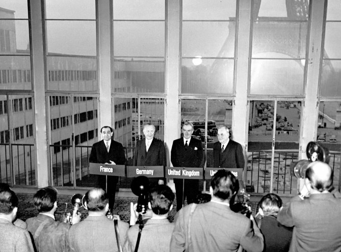 Im Blitzlichtgewitter der Fotografen: Frankreichs Ministerpräsident Pierre Mends-France, Bundeskanzler Konrad Adenauer, Großbritanniens Außenminister Anthony Eden und US-Außenminister John Foster Dulles (v. l. n. r.). Mit der Unterzeichnung der Pariser...