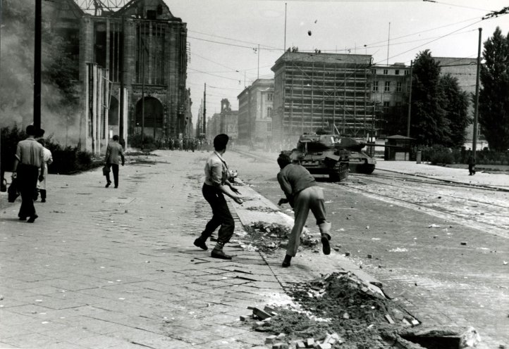 Ein ungleiches Duell: Die Jugendlichen Hans Joachim Maitre (l.) und Erwin Kalisch (r.) gehen in der Leipziger Straße mit Steinen gegen sowjetische Panzer vor. Der 19-jährige Hans Joachim Maitre wird nach dem Aufstand verhaftet und wegen „Anstiftung...