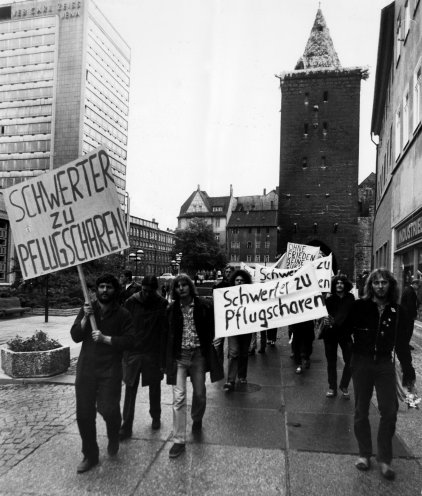 „Schwerter zu Pflugscharen“: Die Friedensgemeinschaft Jena beteiligt sich an offiziellen Kundgebungen mit eigenen Transparenten, die das MfS beschlagnahmt. Im Bild: die Gruppe auf dem Weg zur offiziellen Kundgebung am 19. Mai 1983. Anlass: das FDJ-Pfingstreffens...