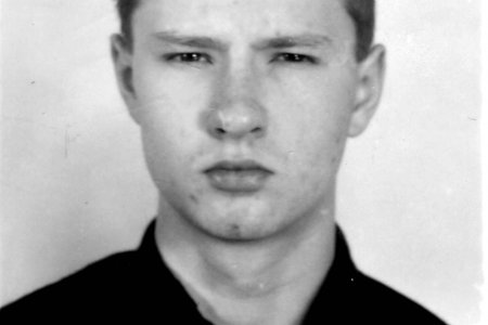 Das Schwarzweißfoto zeigt einen jungen Mann mit kurzen Haaren in einem dunklen Oberteil vor einem hellen Hintergrund. Es handelt sich um ein Porträtfoto mit frontaler Aufnahme des Gesichts.