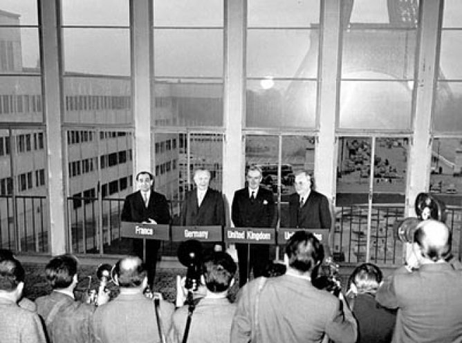 Im Blitzlichtgewitter der Fotografen: Frankreichs Ministerpräsident Pierre Mends-France, Bundeskanzler Konrad Adenauer, Großbritanniens Außenminister Anthony Eden und US-Außenminister John Foster Dulles (v. l. n. r.). Mit der Unterzeichnung der Pariser...