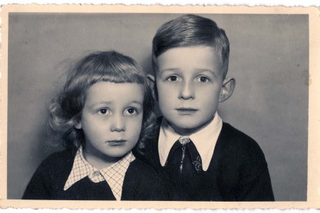 Auf dem Schwarz-Weiß-Porträtfoto sieht man zwei kleine Kinder. Die beiden Kinder tragen ähnliche Kleidung - dunkle Pullover und weiße Hemden mit Kragen. Der Junge auf der linken Seite hat lockiges Haar und der Junge auf der rechten Seite ordentlich gekämmtes Haar.