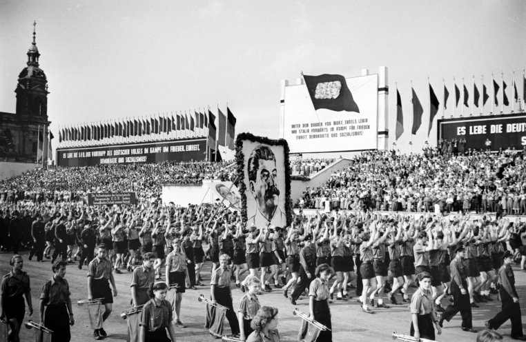 Jugendliche marschieren am 1. Mai 1952 im Gleichschritt an der Staatsführung der DDR vorbei. Stalins Konterfei darf dabei nicht fehlen. Quelle: REGIERUNGonline