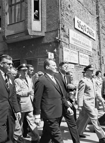 Präsident John F. Kennedy (Mitte) und links neben ihm Willy Brandt, der Regierende Bürgermeister von West-Berlin, auf dem Weg zum Ausländerübergang Checkpoint Charlie. Quelle: REGIERUNGonline/Ludwig Wegmann
